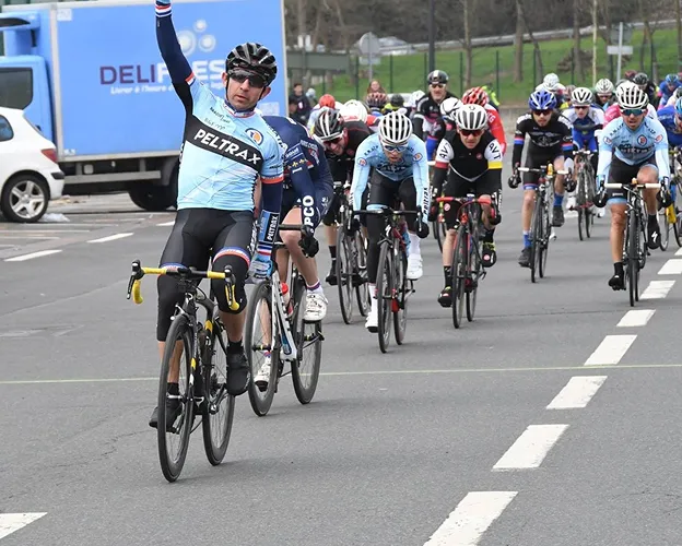 Cycliste en maillot bleu lève le bras, entouré d'autres coureurs à Nogent-sur-Marne dans le Val-de-Marne près de Montreuil 
