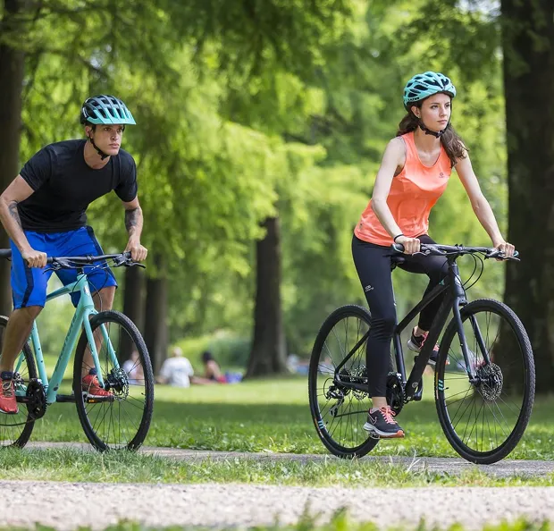 Deux personnes portant des casques font du vélo sur un chemin de parc verdoyant à Nogent-sur-Marne dans le Val-de-Marne près de Montreuil