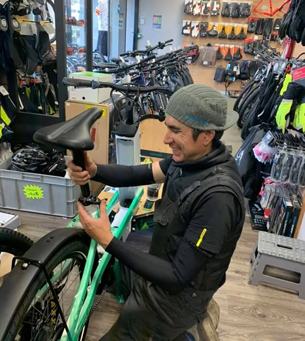 Un homme assemble une selle sur un vélo vert dans un magasin de vélos à Nogent-Sur-Marne dans le Val-de-Marne près de Montreuil
