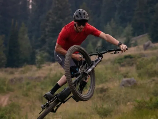 Cycliste en VTT, en l'air sur une roue, chemise rouge et casque à Nogent-sur-Marne dans le Val-de-Marne près de Montreuil 
