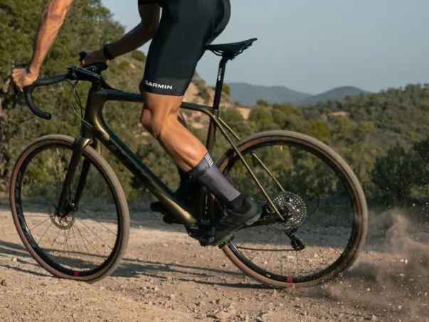 Cycliste sur un vélo de gravel doré, pédalant sur un chemin de terre avec de la poussière à Nogent-sur-Marne dans le Val-de-Marne près de Montreuil 