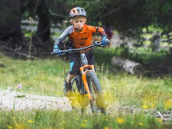 Jeune garçon en tenue de VTT orange et bleue, sur un chemin forestier à Nogent-sur-Marne dans le Val-de-Marne près de Montreuil 