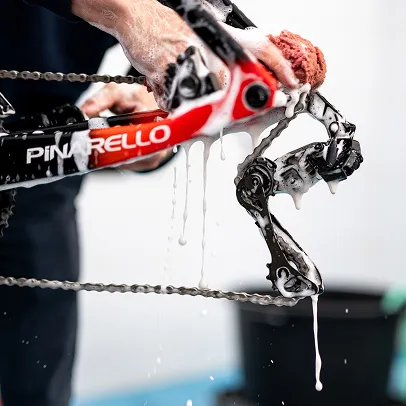 Personne lavant un vélo Pinarello rouge et noir, dégoulinant de mousse blanche à Nogent-sur-Marne dans le Val-de-Marne près de Montreuil 